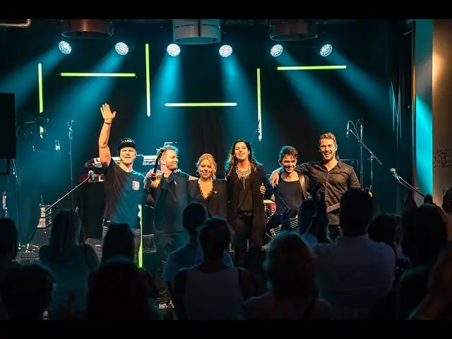 Live-Musik-Performance mit energiegeladenen Sängerinnen und Musikern bei mitreißendem Licht-Showeffekt.