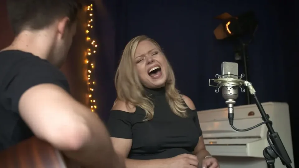 Emotionale Sängerin bei Livemusik mit Gitarre, warmem Licht und gemütlicher Atmosphäre.