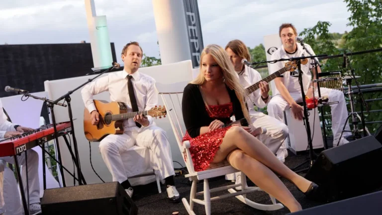 Musik im Freien: Sängerin in rotem Kleid und Musiker bei Gartenparty im Sommer.