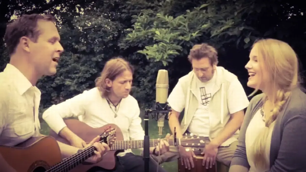 Musiker beim entspannten Outdoor-Jam mit Gitarre, Cajón und Freude in der Natur.
