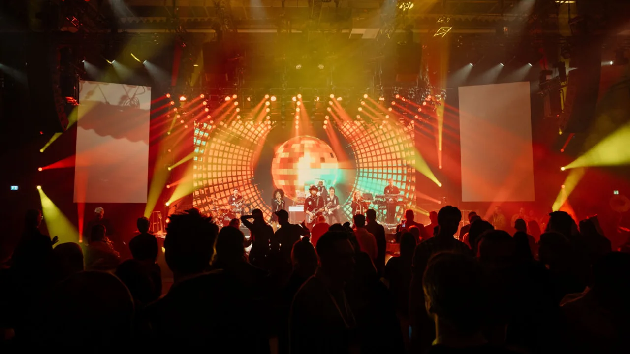 Live-Musikfestival mit Bühne, Neonlichtern, tanzender Menschen und energiegeladenen Performances.