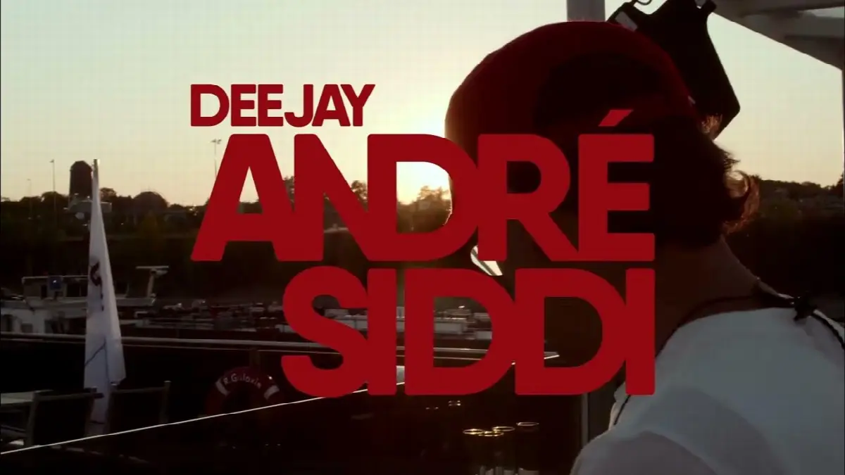 Deejay André Siddi bei Sonnenuntergang am Wasser mit Booten und Festivalatmosphäre.