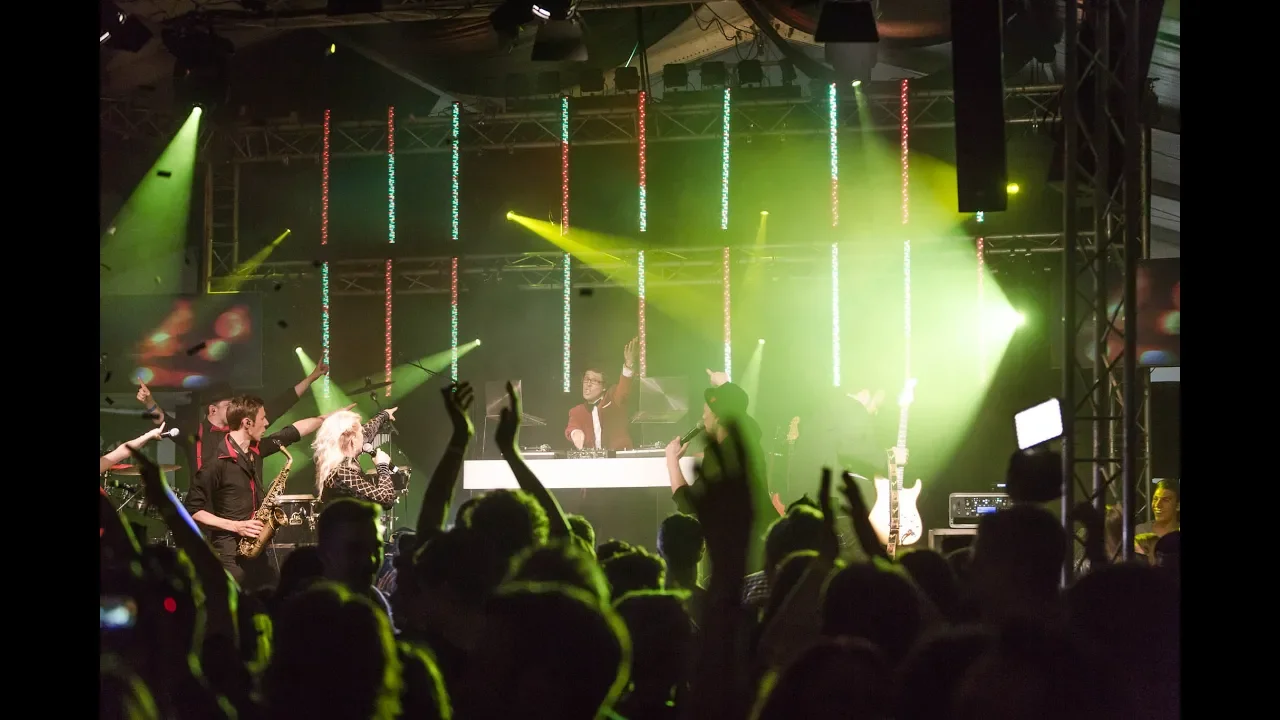 Live Musik Konzert mit DJ, Saxophon, bunter Lichtshow und tanzender Crowd.