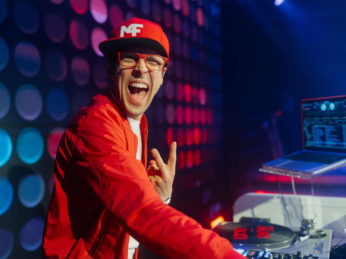 DJ Andre Siddi in rotem Outfit mit Mixer, leuchtende Lichter und Partystimmung bei Live-Musik.