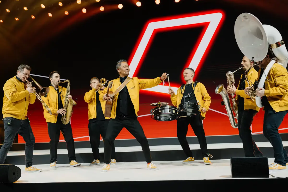 Brassband-Auftritt bei Preisverleihung mit energiegeladenen Musikern in gelben Jacken.