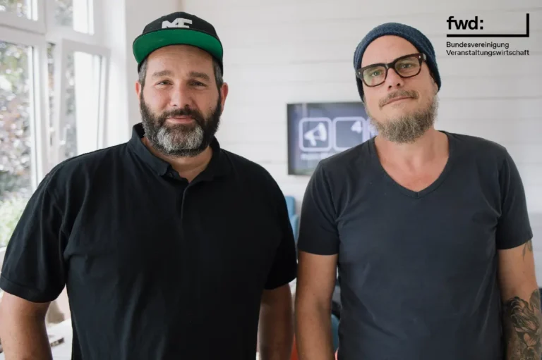 Zwei Männer im modernen Co-Working-Bereich, entspannt und professionell, mit Veranstaltung und Kommunikation im Fokus.