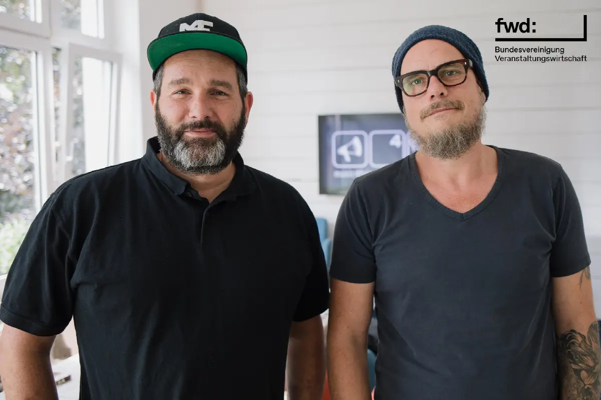Zwei Männer im modernen Co-Working-Bereich, entspannt und professionell, mit Veranstaltung und Kommunikation im Fokus.