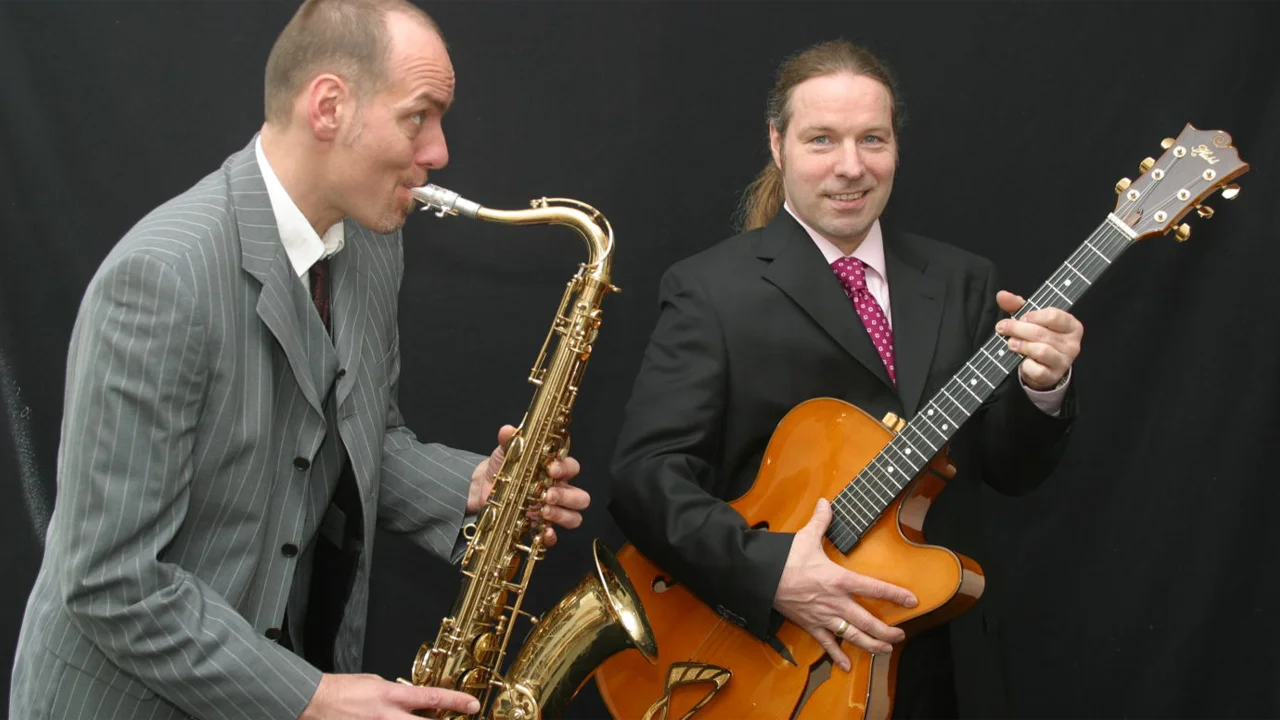 Jazzmusiker mit Saxophon und Gitarre, live Performance, stilvolle Kleidung, musikalische Zusammenarbeit.