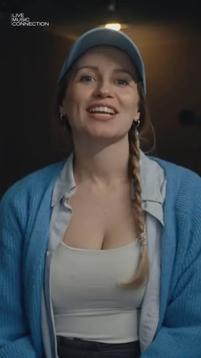 Junge Frau bei Live-Musik-Event mit freundlichem Lächeln und Casual-Stil.