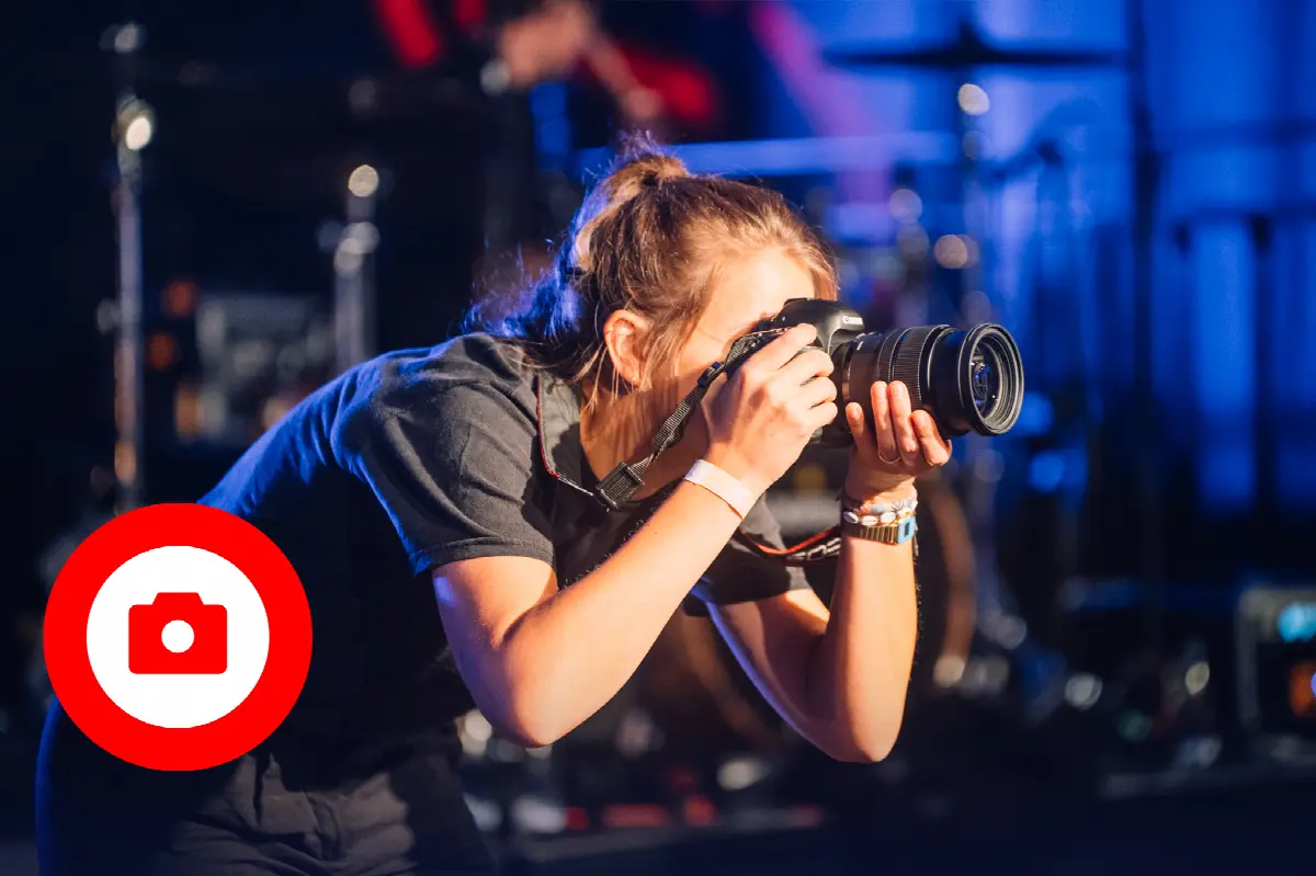 Junge Fotografin fotografiert live Musik mit professioneller Kamera bei einem Konzert.