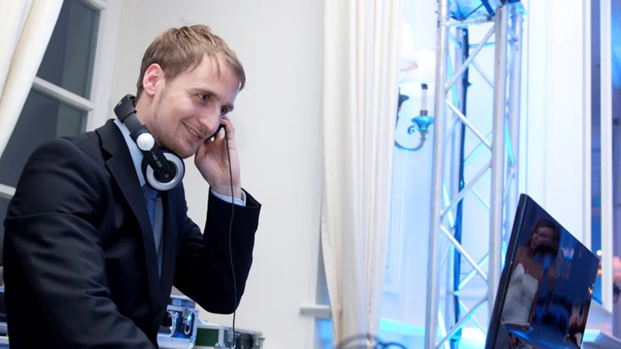 Professioneller DJ in Anzug mit Kopfhörern bei Party mit eleganter Beleuchtung.