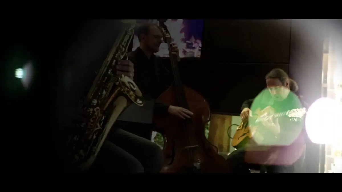 Jazzmusik-Performance mit Saxophon, Kontrabass und Gitarre in gemütlicher, stimmungsvoller Atmosphäre.