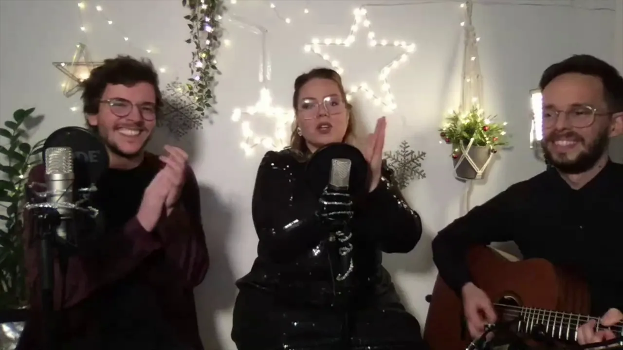 Festliche Musikerperformance mit Gesang, Gitarre und fröhlicher Stimmung im Weihnachtsambiente.