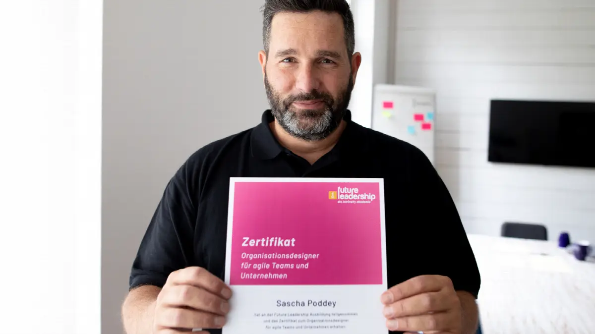 Mann hält Zertifikat für Organisationsdesign in Agile Teams bei Future Leadership.