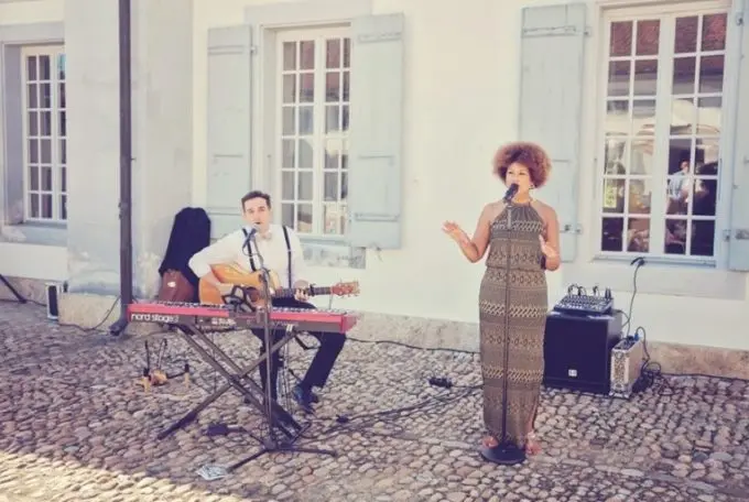 Live-Musik im Außenbereich: Musiker, Gitarre & Gesang vor charmantem Stadthaus bei Sonnenschein.