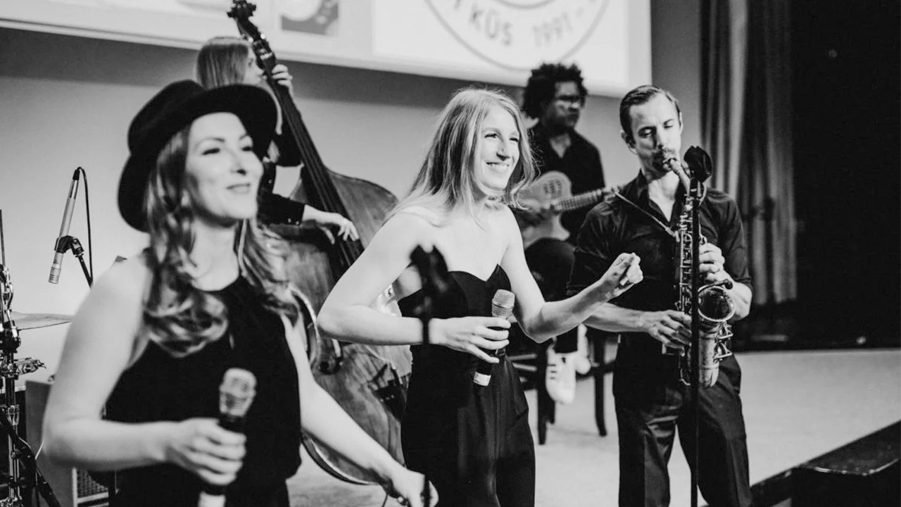 Live-Musikshow mit zwei Sängerinnen, Band und klassischer Atmosphäre in Schwarz-Weiß.