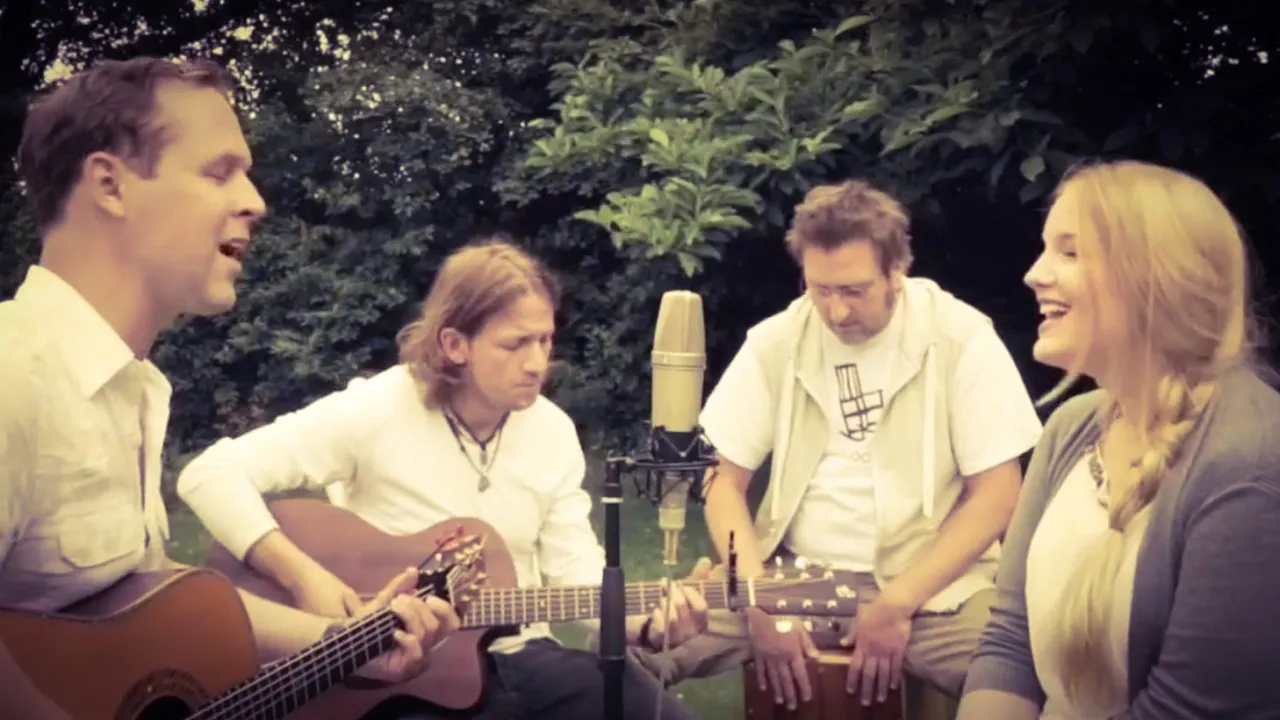 Musiker beim akustischen Live-Auftritt im Grünen mit Gitarre, harmonischer Gesang und entspannter Atmosphäre.